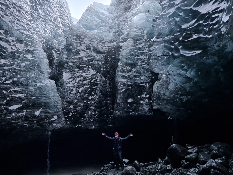 Homme debout dans une grande grotte glacée.