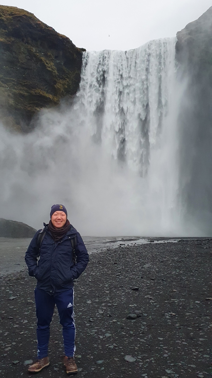 Homme debout devant une grande cascade.