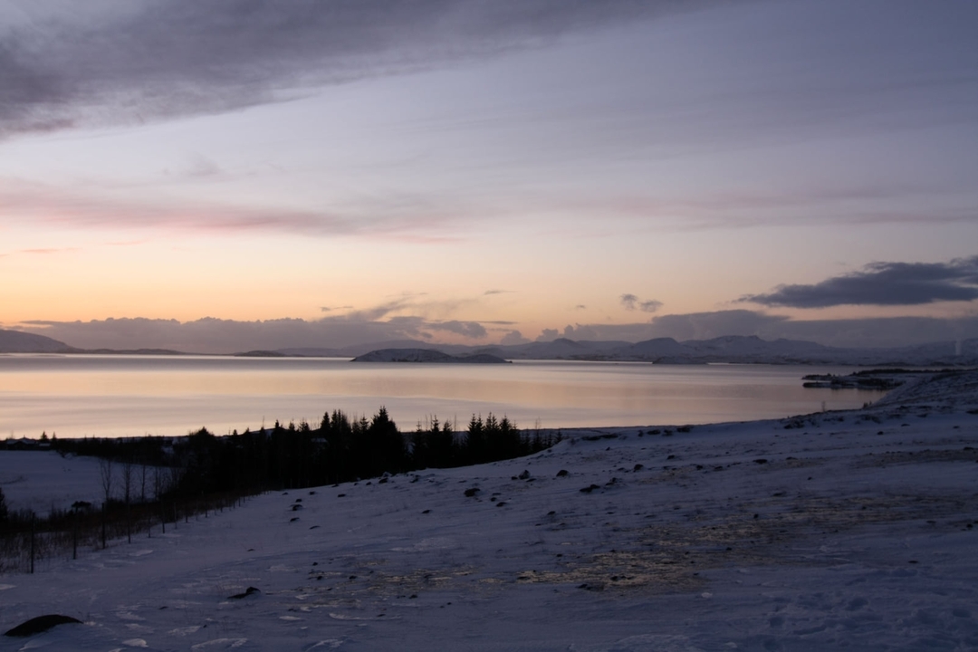 Paysage enneigé avec un lac serein au coucher du soleil.