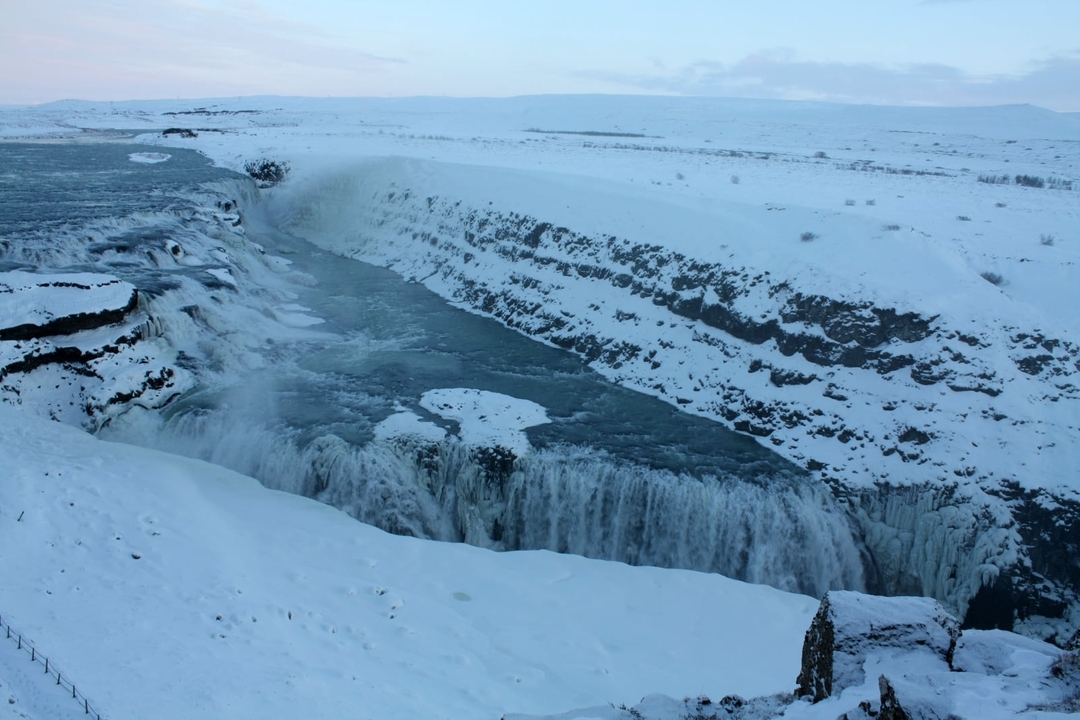Une grande cascade entourée d'un terrain enneigé.