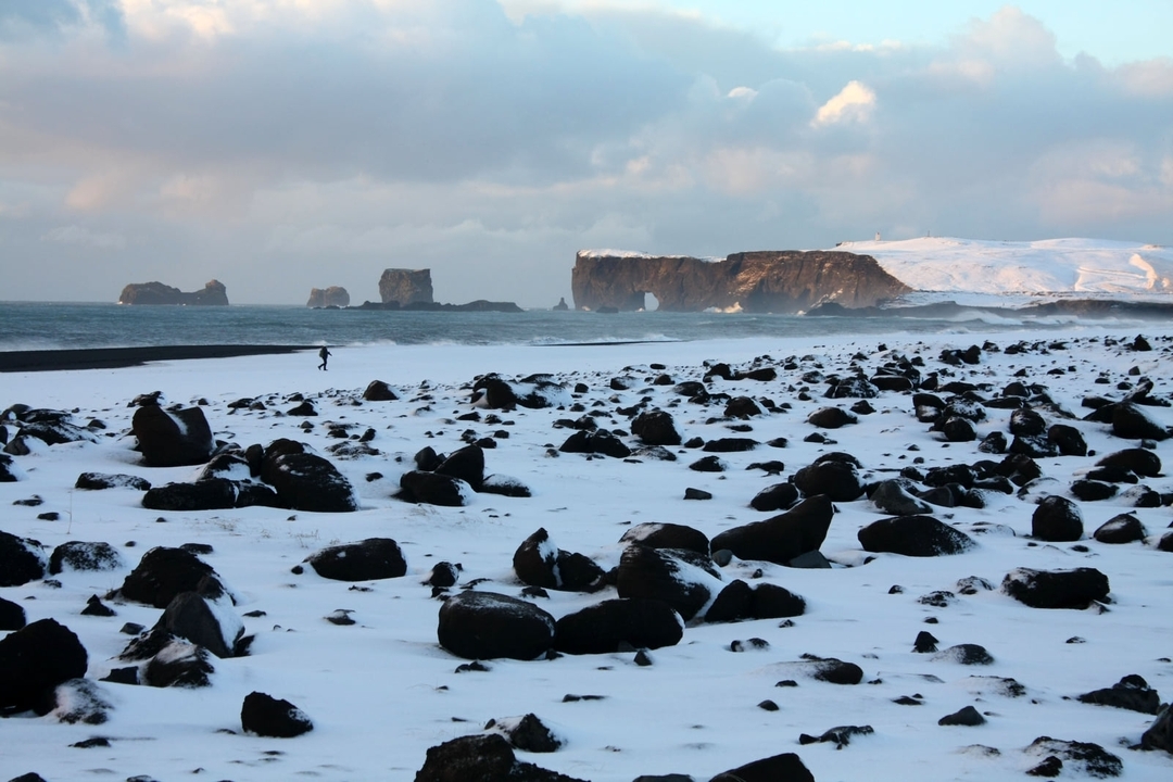 Plage rocheuse avec de la neige et des aiguilles marines au loin au coucher du soleil.
