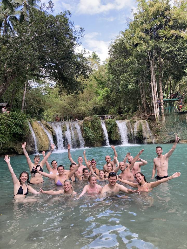 Large group of people enjoying themselves at a waterfall.