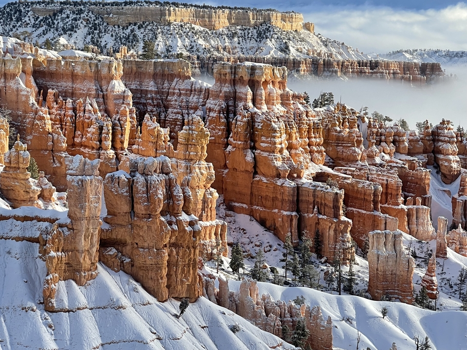 Bryce Canyon's orange and white rock formations with light snow.