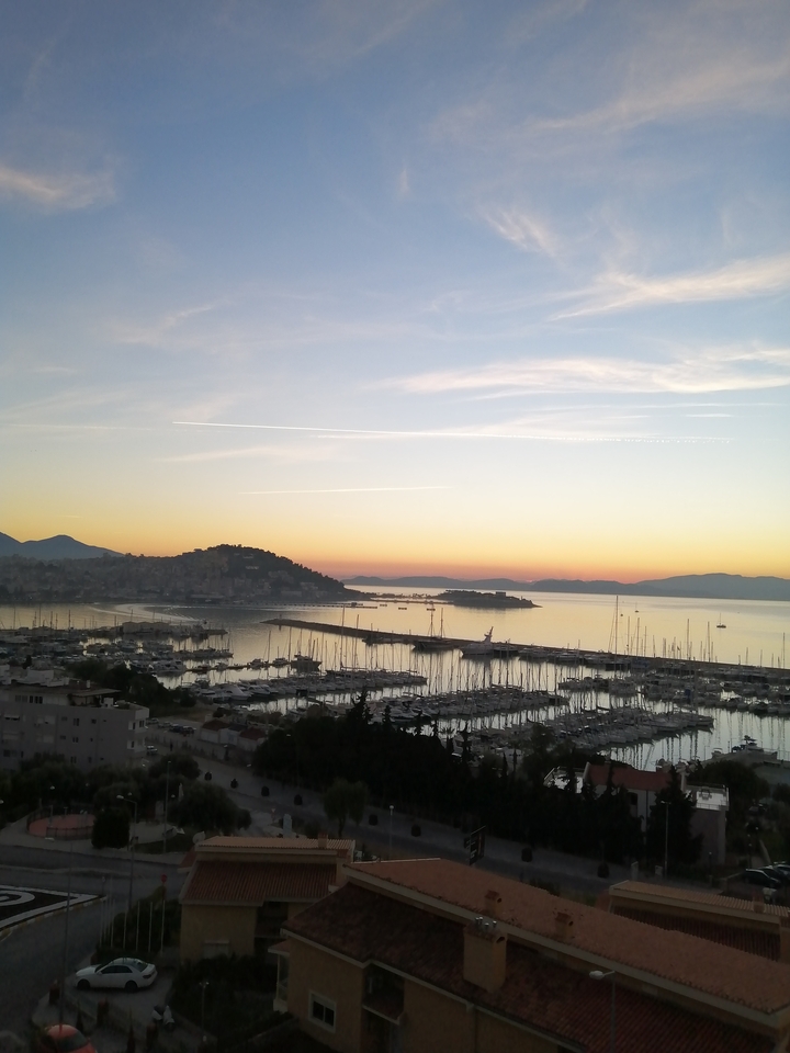 Marina at sunset with boats and hills in the background