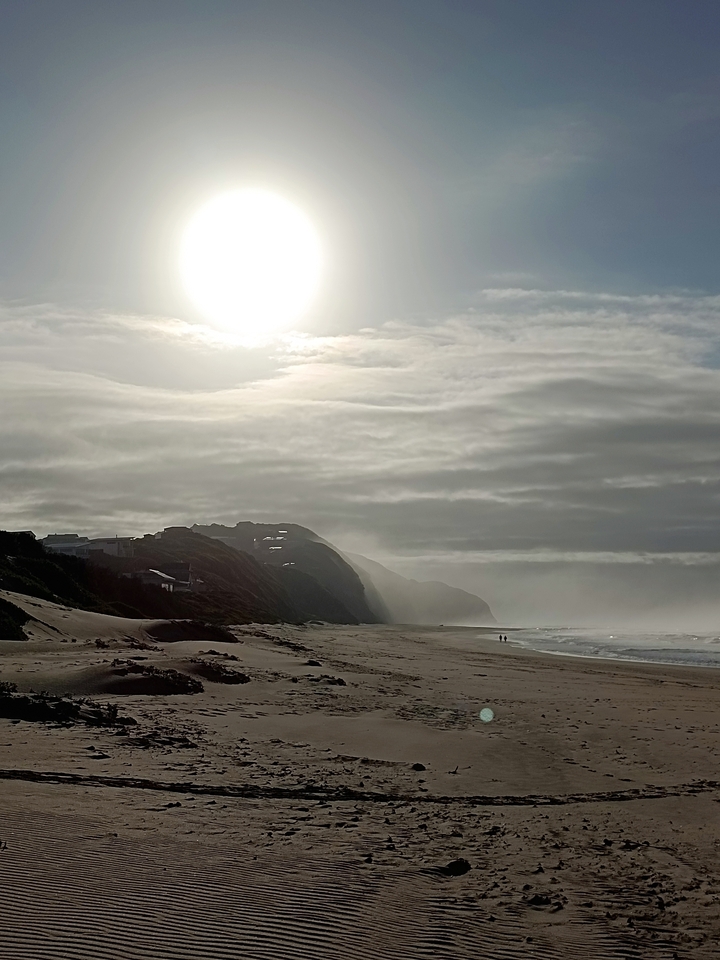 Une scène de plage avec des falaises et un ciel nuageux.