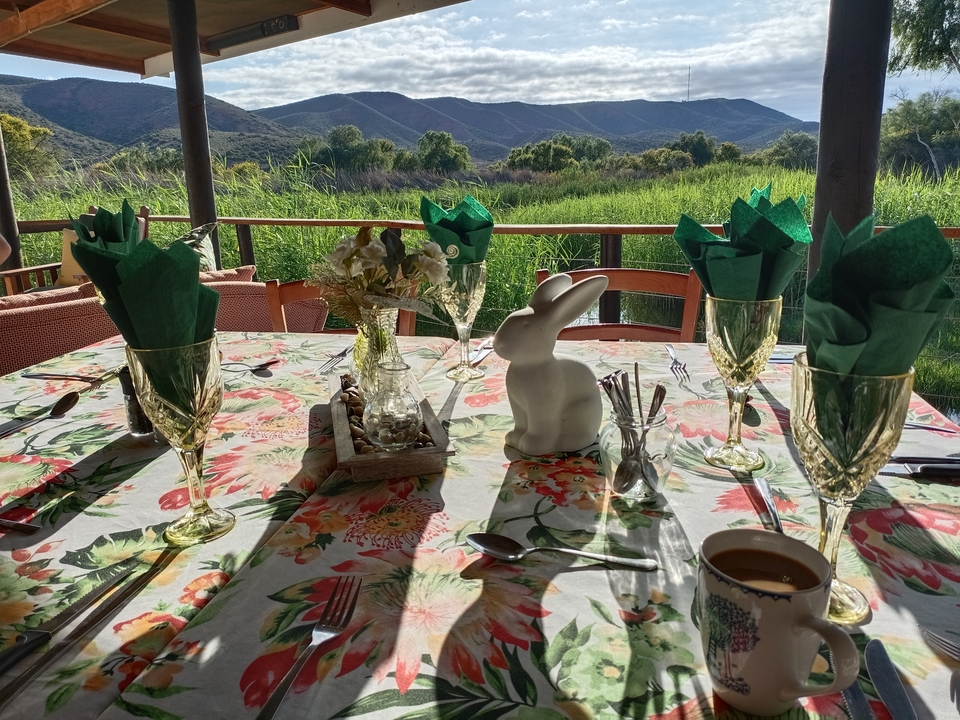 A table setup with glasses and napkins, outdoors with a view.