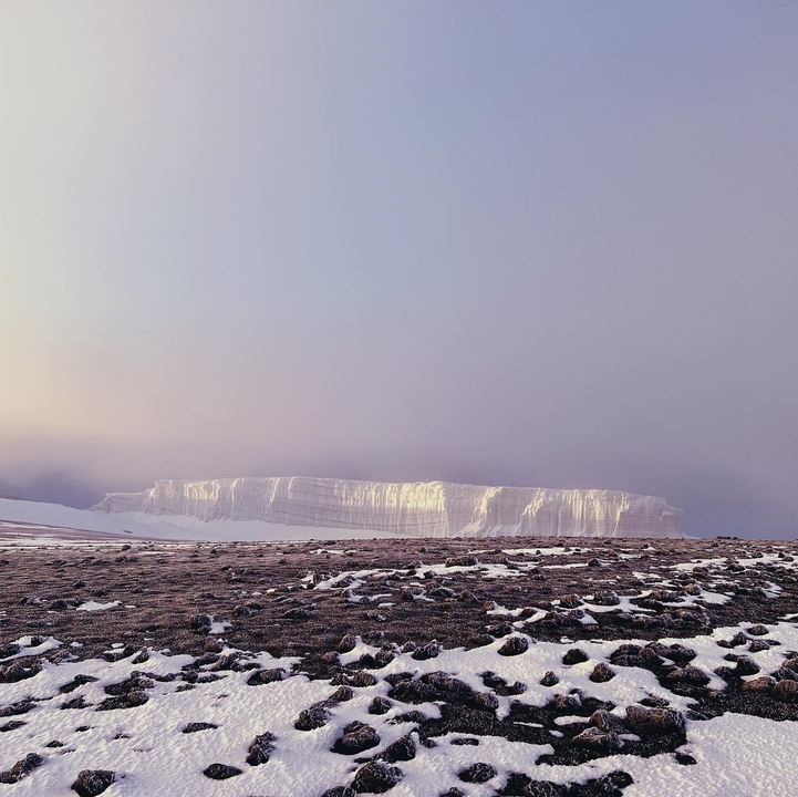 A large white glacier with a rocky foreground.