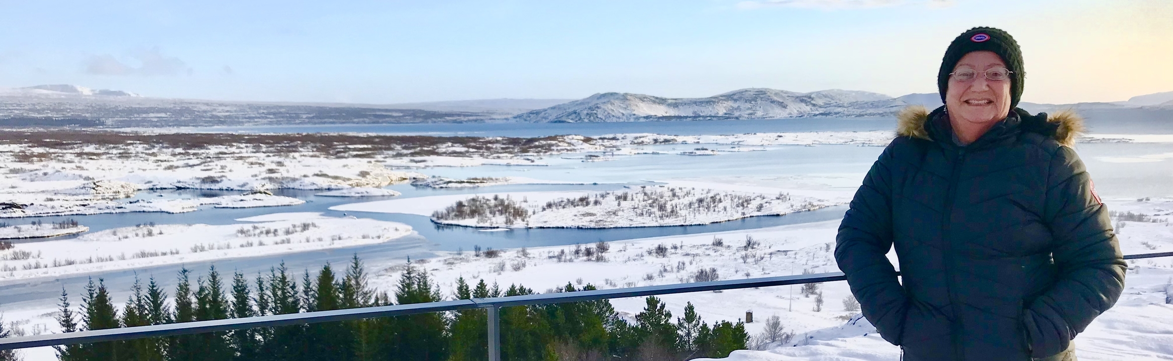 Snowy landscape with a partially visible fence and a person on the side.
