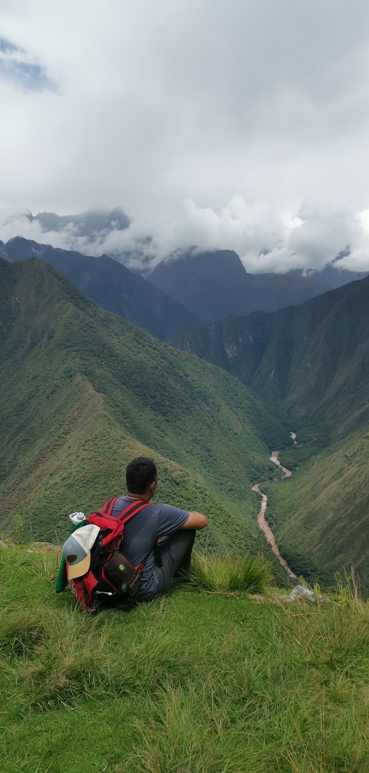 Person overlooking a verdant valley with a river.