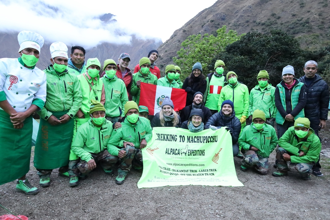 Group of hikers posing with a banner for trekking to Machu Picchu.