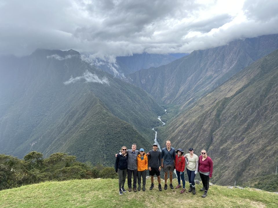 Group of people standing on a ridge with a scenic valley view.