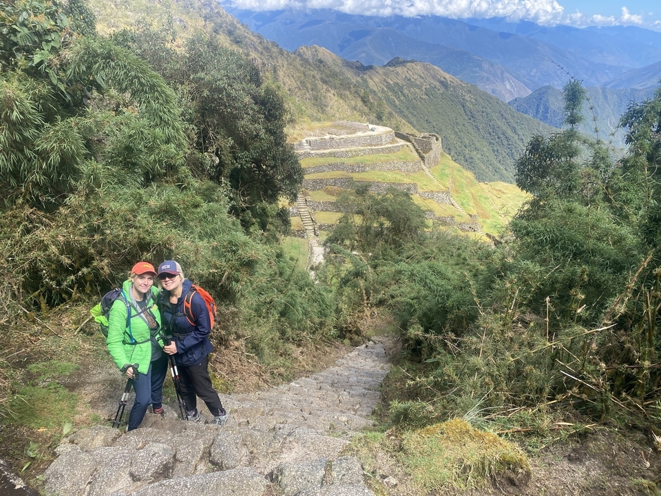 Two hikers on a stone pathway amidst ancient ruins.