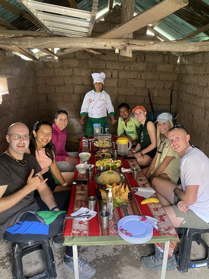 Group dining with local trekkers on a table filled with food.