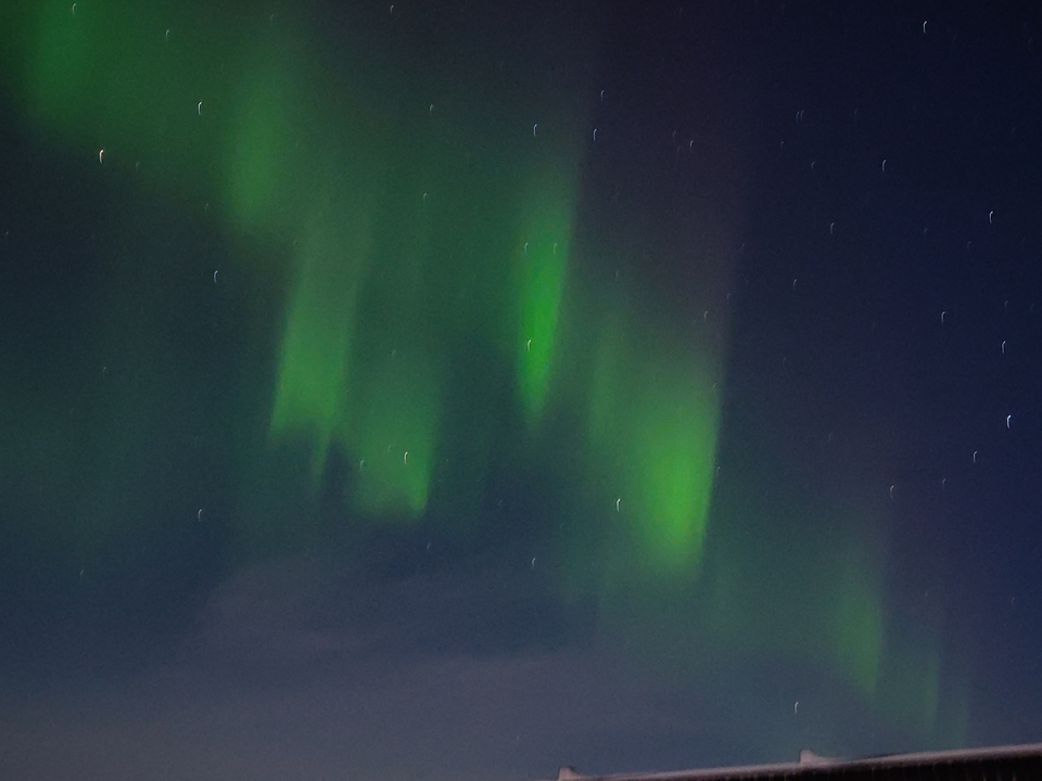 Aurora boreal verde danzando sobre un cielo nocturno.
