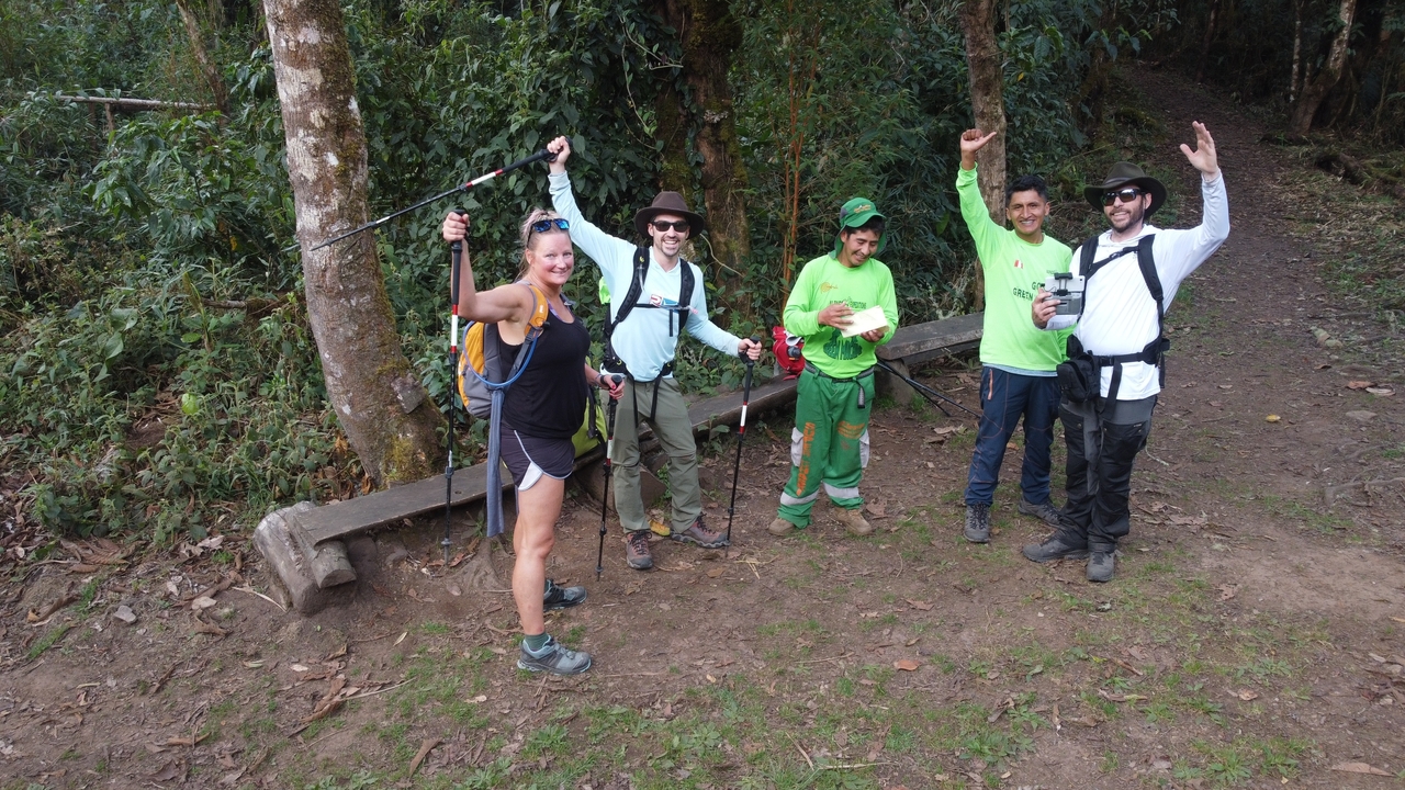 A group of hikers posing with trekking poles in a forest area.