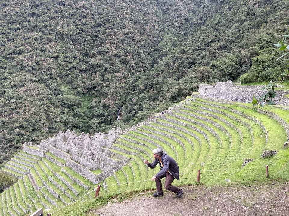 A person posing humorously with ancient terraces.