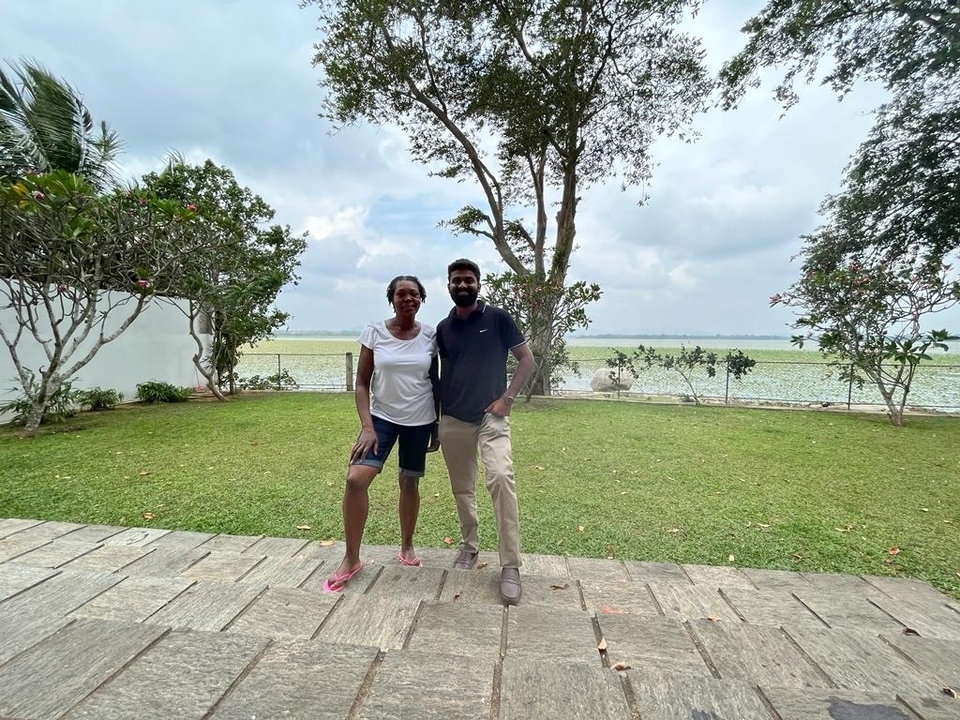 Two people standing in front of a serene lake.