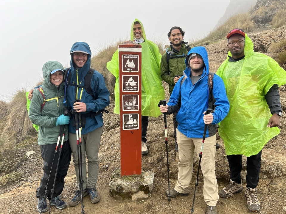 A group of hikers posing near a trail sign.
