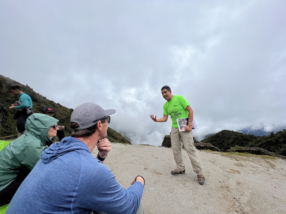 A guide explaining something to a group of hikers in a mountainous area.