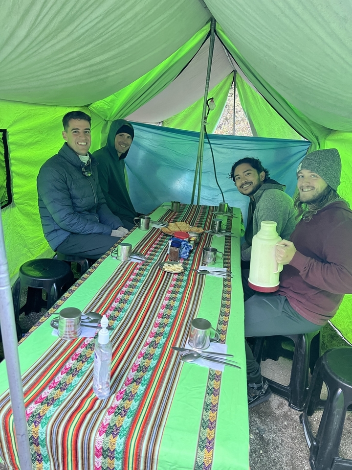 Group of people inside a tent having a meal.