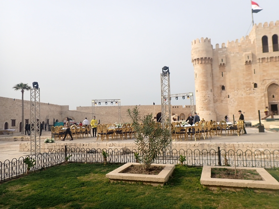 People setting up for an outdoor event in a historic fort.