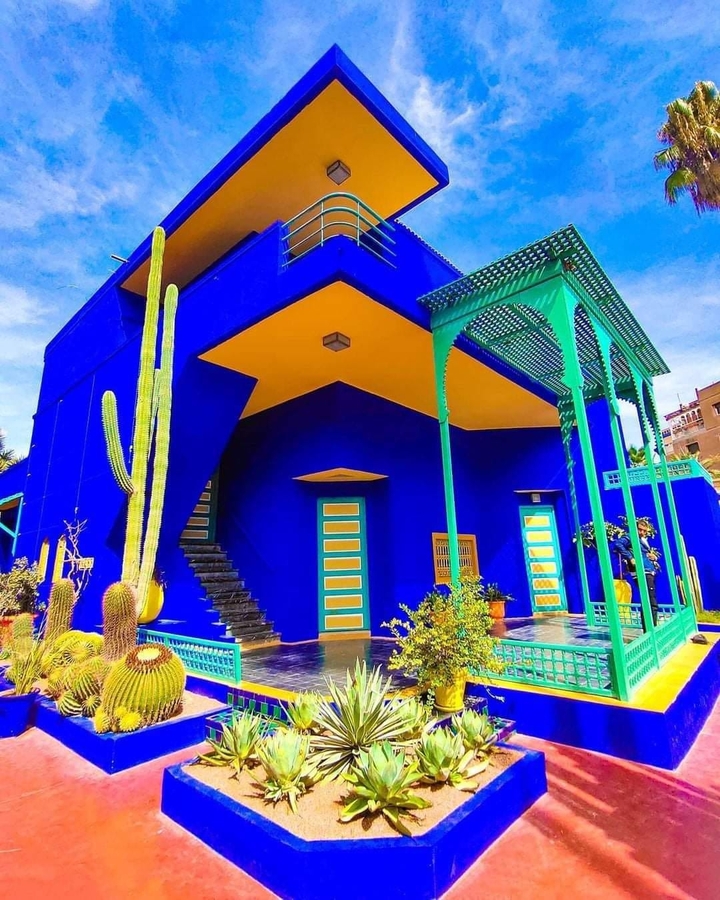 Colorful building with vibrant blue walls and cacti in the garden.