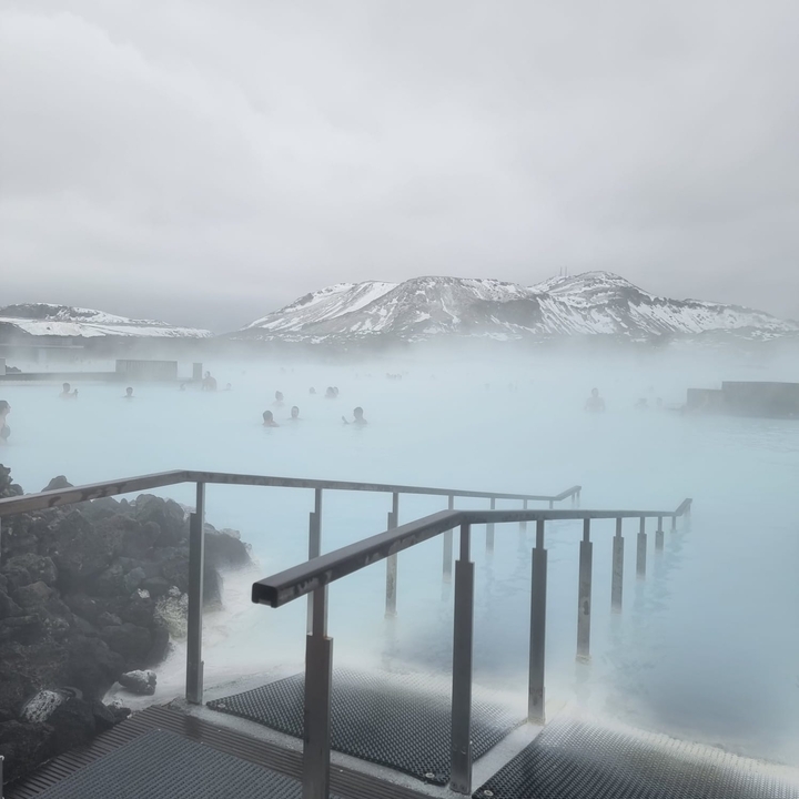 Hot spring with people relaxing in the misty blue water.