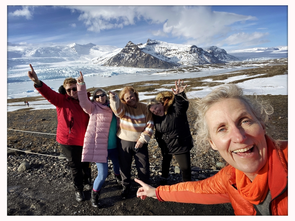 Grupo de personas posando frente a montañas cubiertas de nieve.