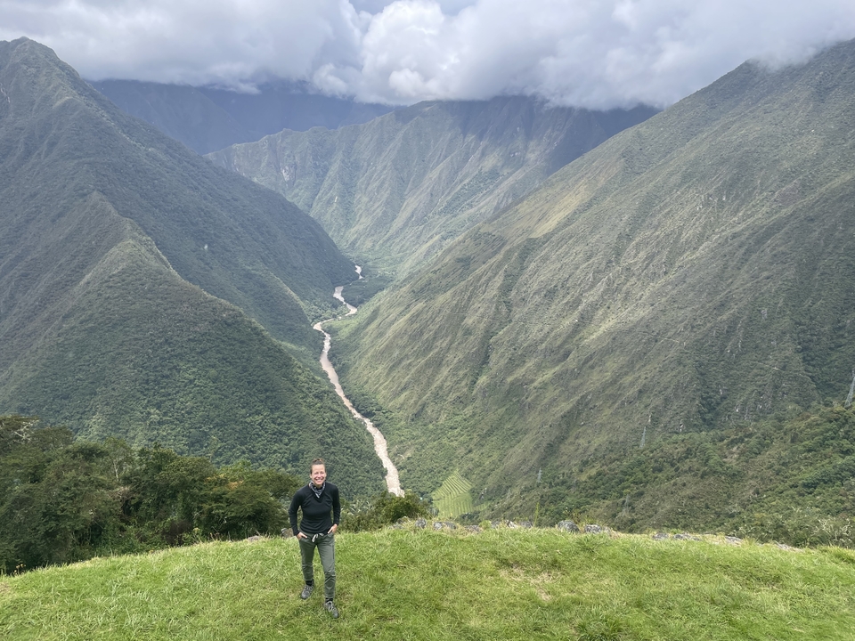 Man posing in front of mountain view with river in valley.