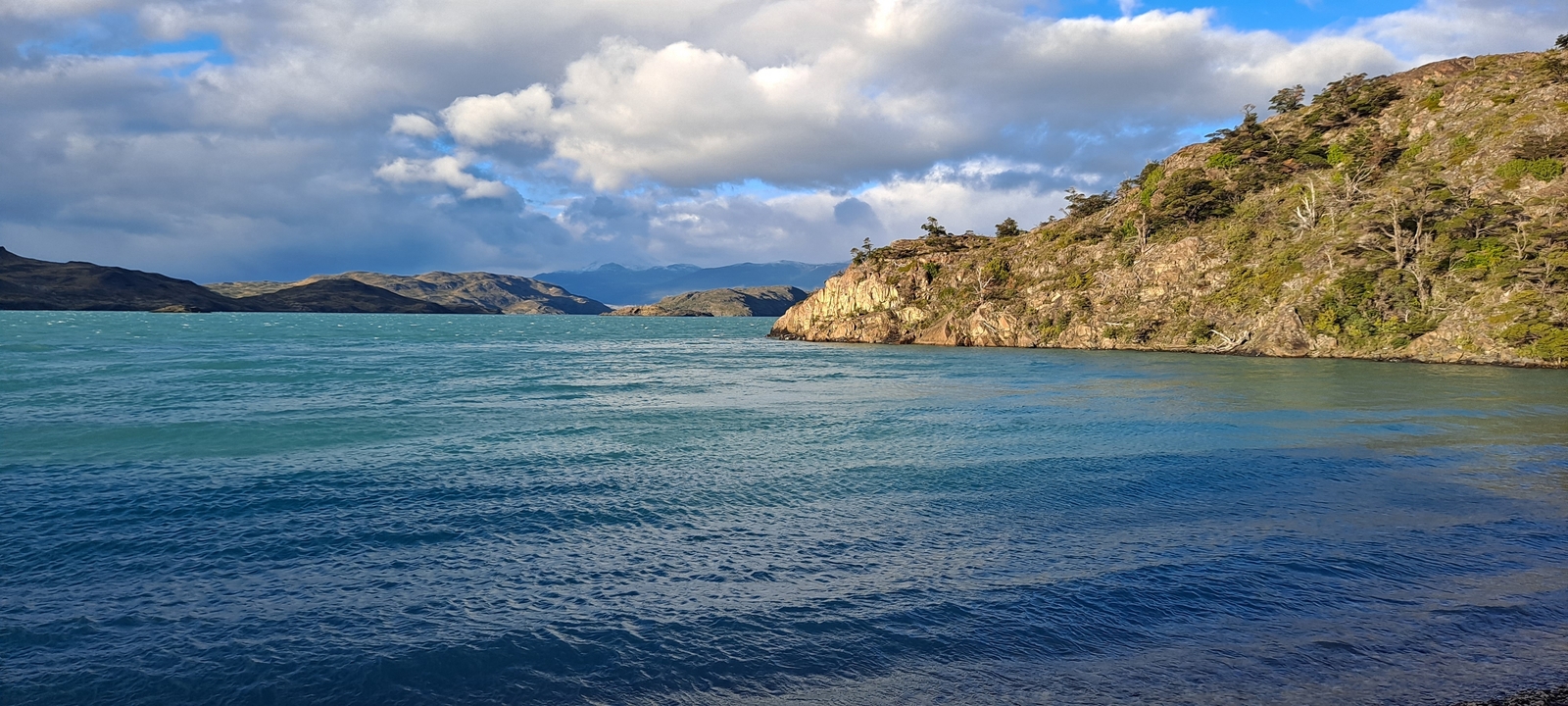 A view of a lake with surrounding hills and clear sky.