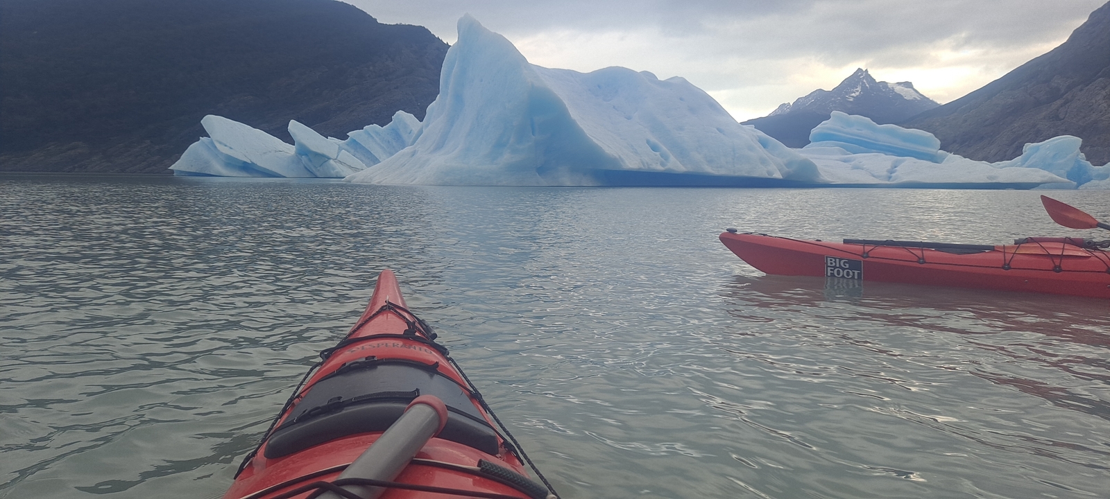 Kayaks in the water near icebergs.