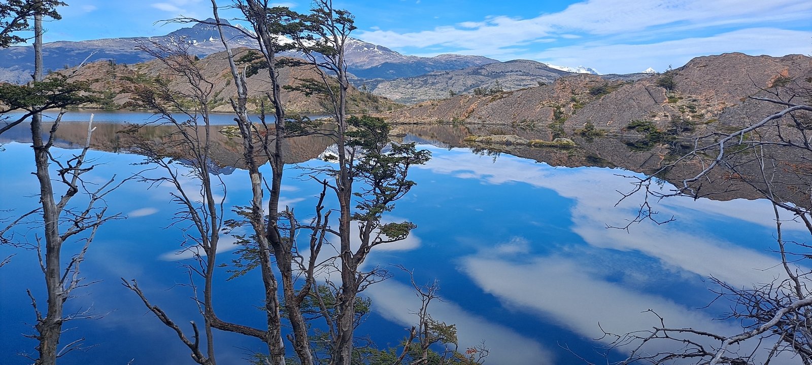 A lake with a reflection of the sky and mountains.