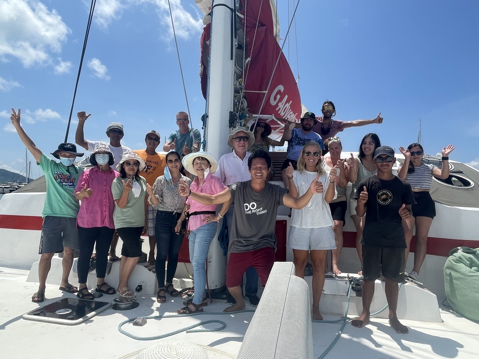 Photo de groupe sur un voilier par ciel dégagé.