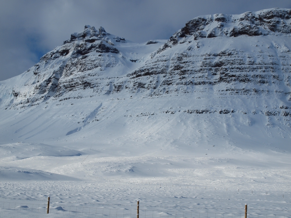 Paisaje montañoso cubierto de nieve bajo un cielo azul.