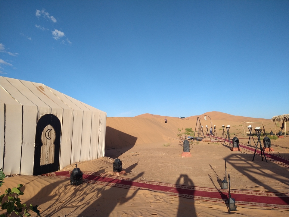 Desert camp with tents and sand dunes in the background.