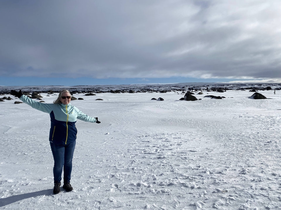 A person standing on a snowy landscape with a vast sky.