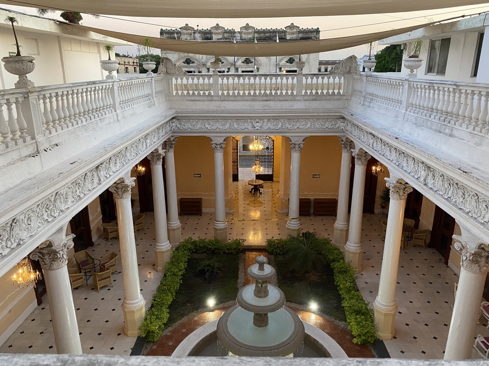 Interior of a grand historic building with columns and chandeliers.
