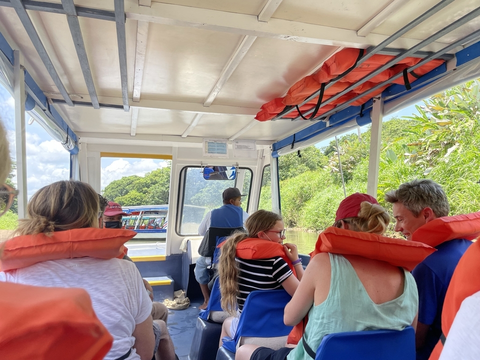 Groupe de personnes dans un bateau avec des gilets de sauvetage sur une rivière.