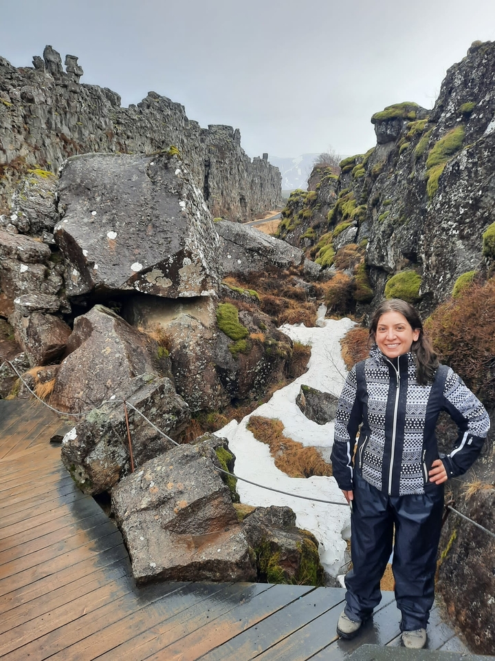 Woman hiking through rocky terrain with patches of snow.