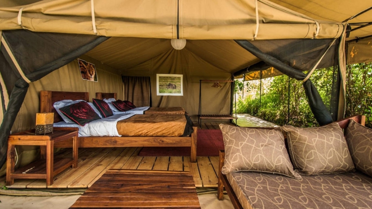 Luxury tent interior with bed and seating area.