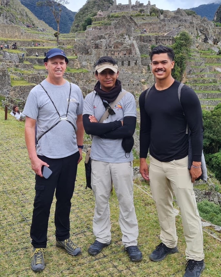Groupe d'hommes posant sur une colline du Machu Picchu.