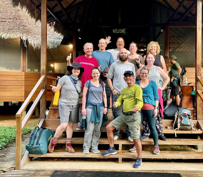 Groupe de personnes posant sur les marches d'un pavillon dans un cadre tropical.