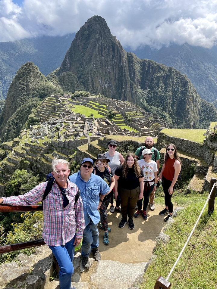 Groupe de touristes posant avec le Machu Picchu en arrière-plan.