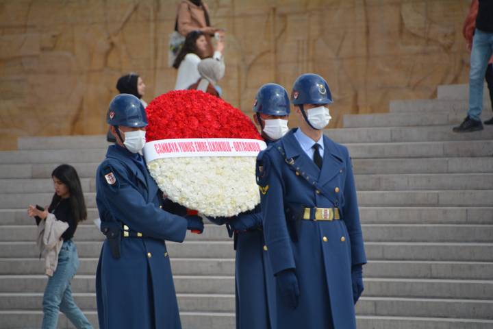 Des gardes en uniforme tenant une couronne de fleurs avec un groupe de spectateurs.