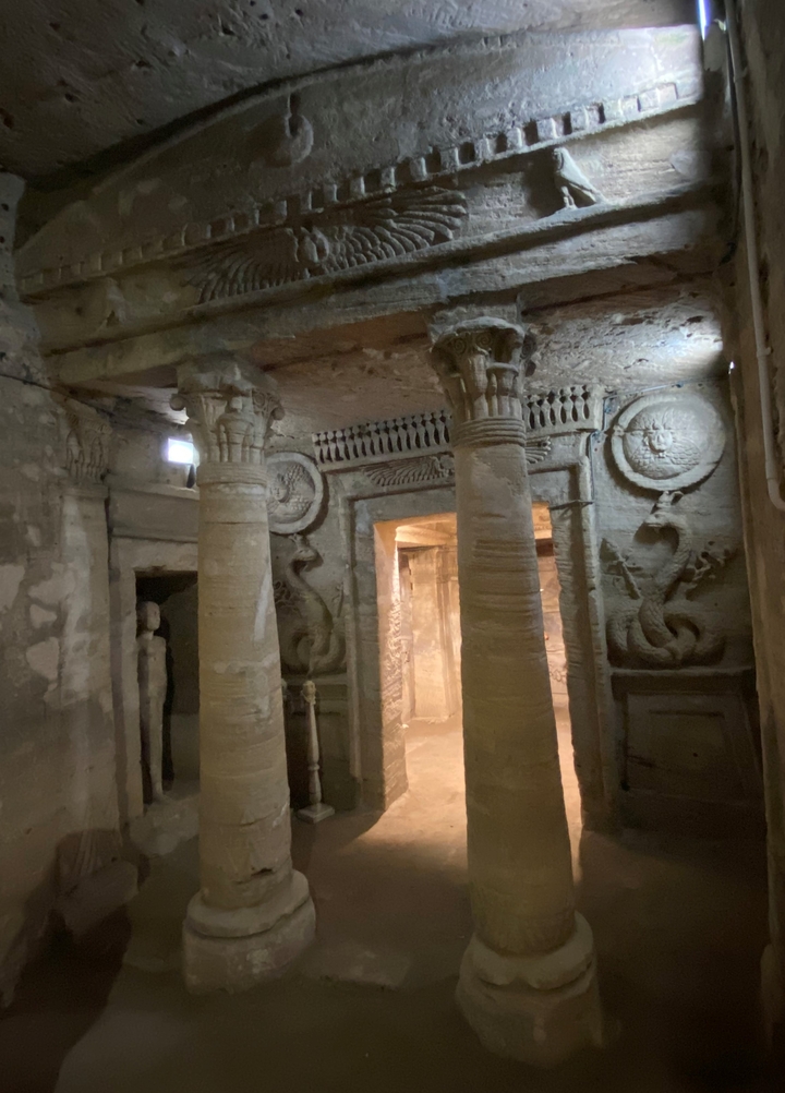 Ancient columns and carvings in an underground structure.