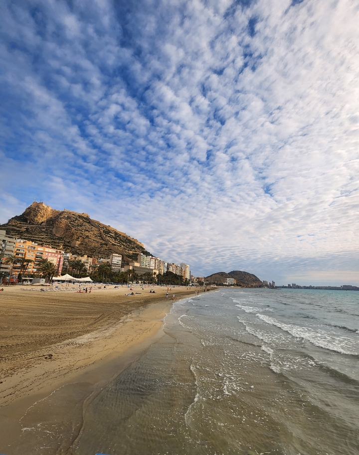 Scenic beach with cityscape and mountains.