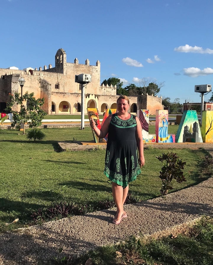 Person posing in front of a historical building with murals.