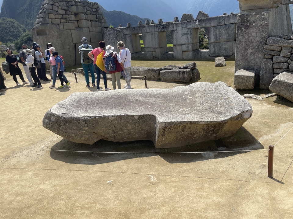 Tourists observing a large stone at an archaeological site.
