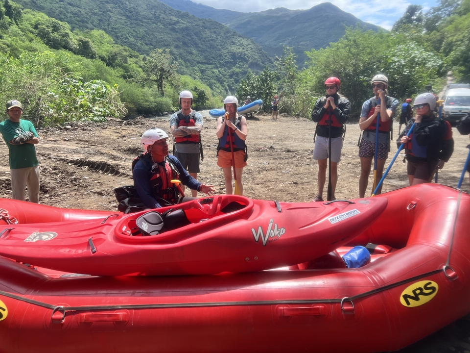 People preparing for a rafting adventure with red rafts.
