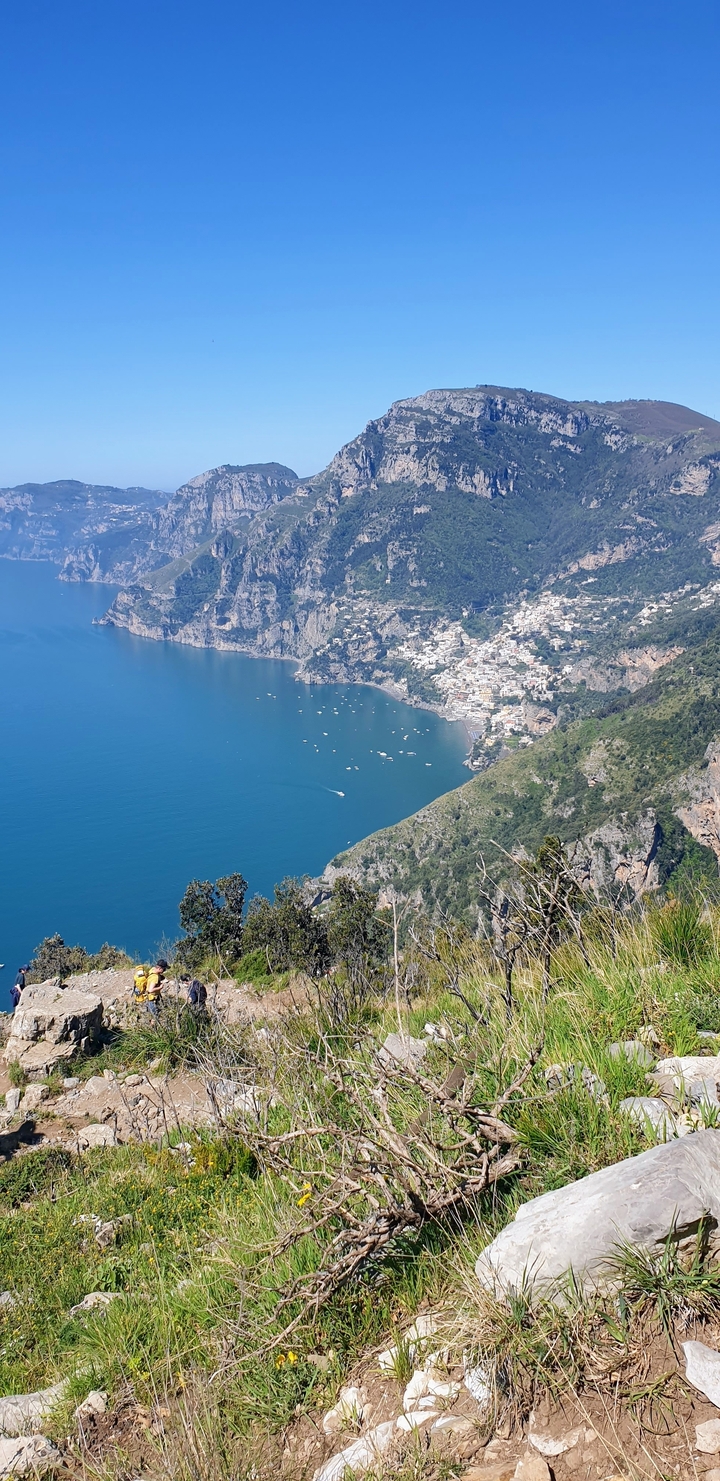 A panoramic view of a coastline with a town and clear blue sea.
